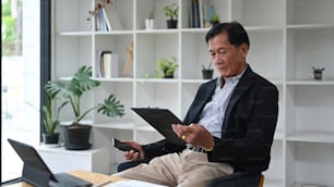 Uomo d'affari maturo che lavora con il tablet del computer e analizza i rapporti finanziari in ufficio.