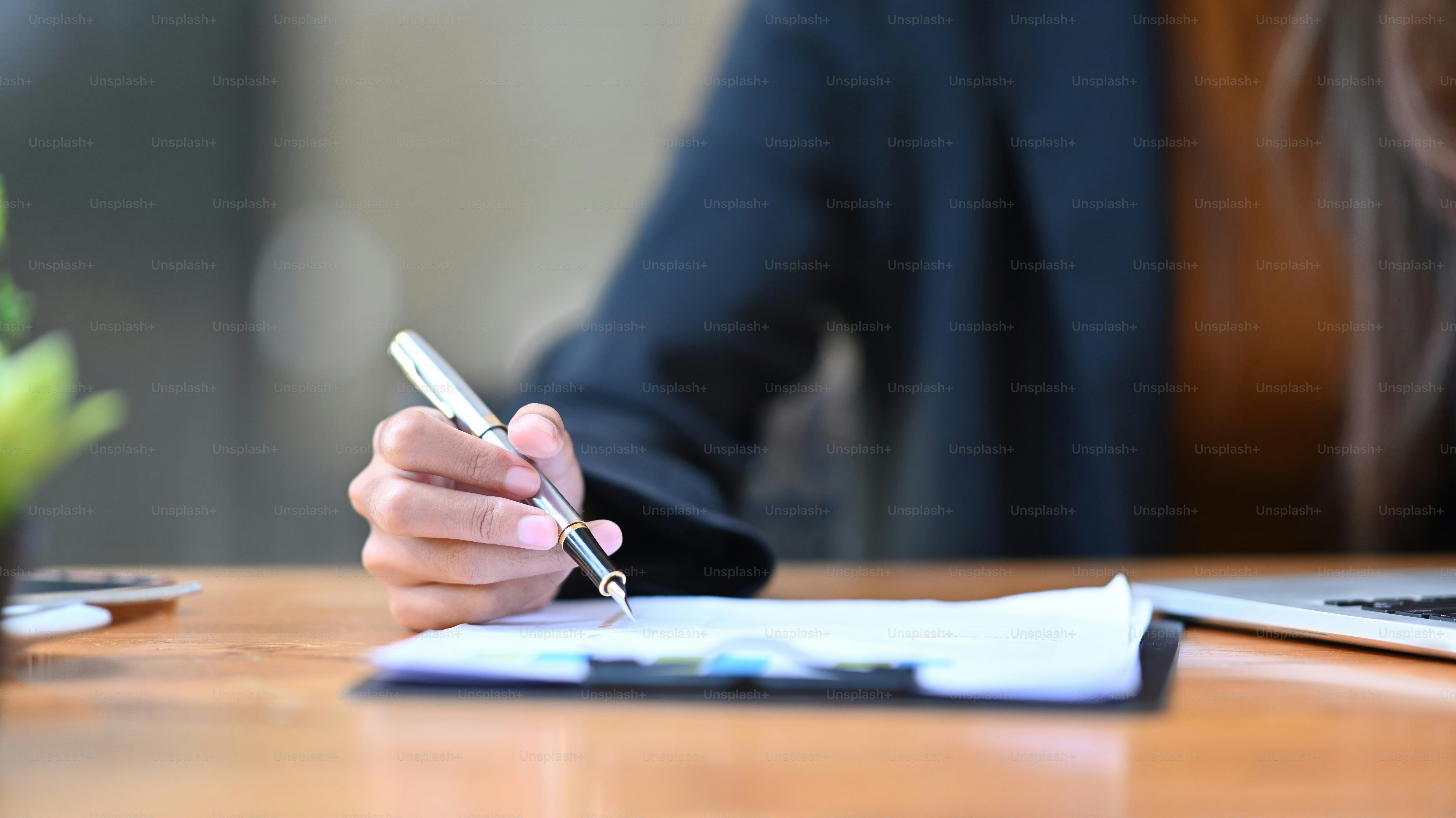 Cropped shot businesswoman holding pen and signing on document.