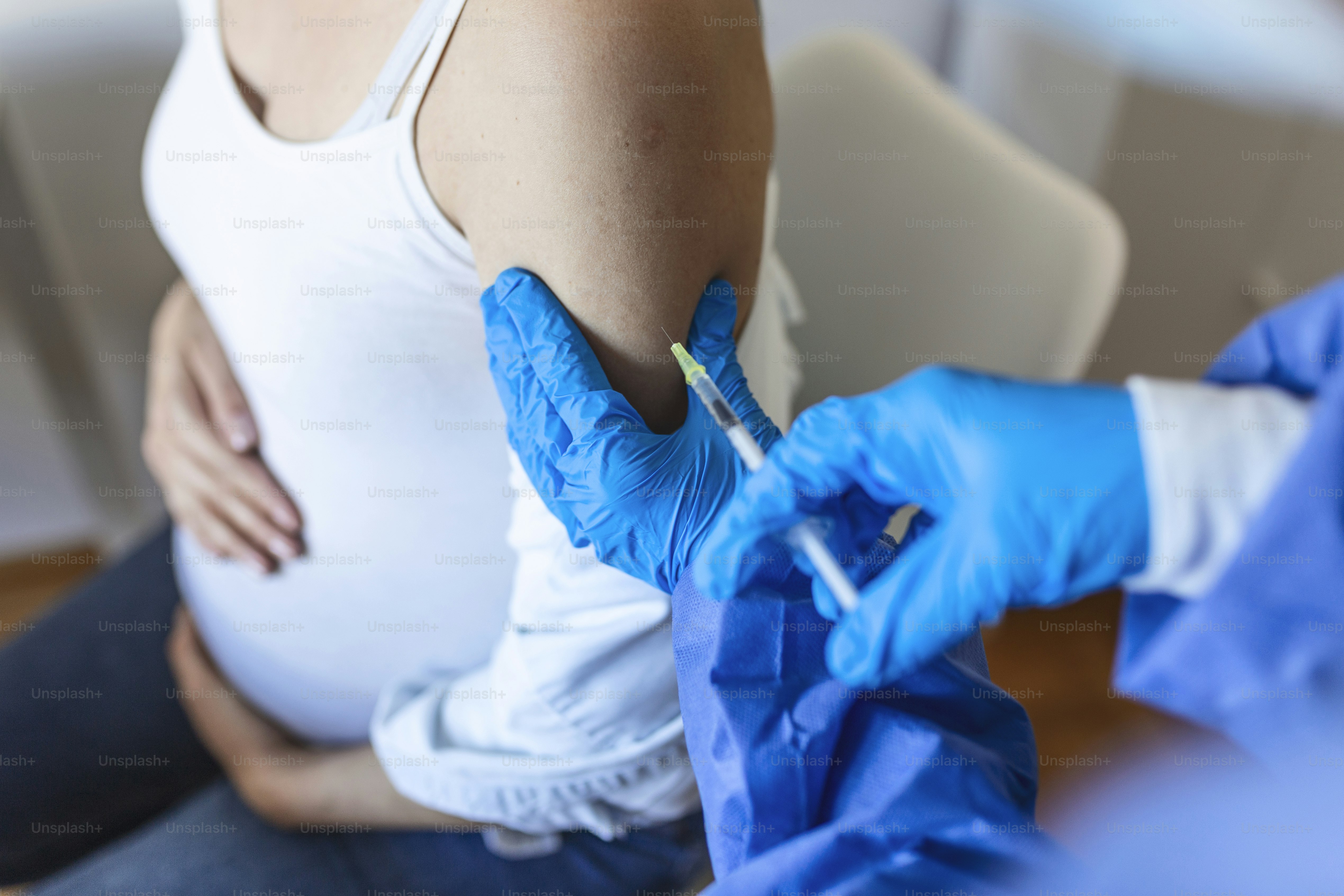 Pregnant Vaccination. Doctor giving COVID -19 coronavirus vaccine injection to pregnant woman. Doctor Wearing Blue Gloves Vaccinating Young Pregnant Woman In Clinic. People vaccination concept.
