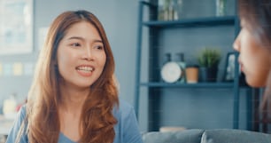 Asia housewife women with casual relax on couch with cup of tea talk together about their life and husband relationship gossip in living room at house.
