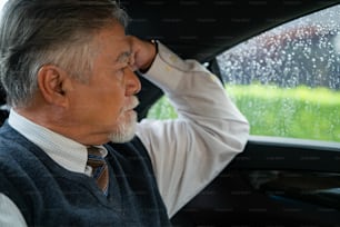 Vertrauen Senior Geschäftsmann im Anzug, der auf dem Rücksitz des Autos sitzt und Geschäftsplan denkt, während er zur Arbeit im Büro geht. Älterer CEO, der im Automobil arbeitet und den Verkehr aus dem Fenster betrachtet