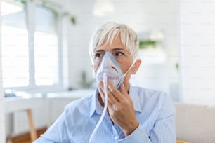 酸素マスクを吸入している病気の高齢女性、肺炎コロナウイルスのパンデミック。酸素マスクを着用し、治療を受けている病気の高齢女性。COVID19の高齢女性