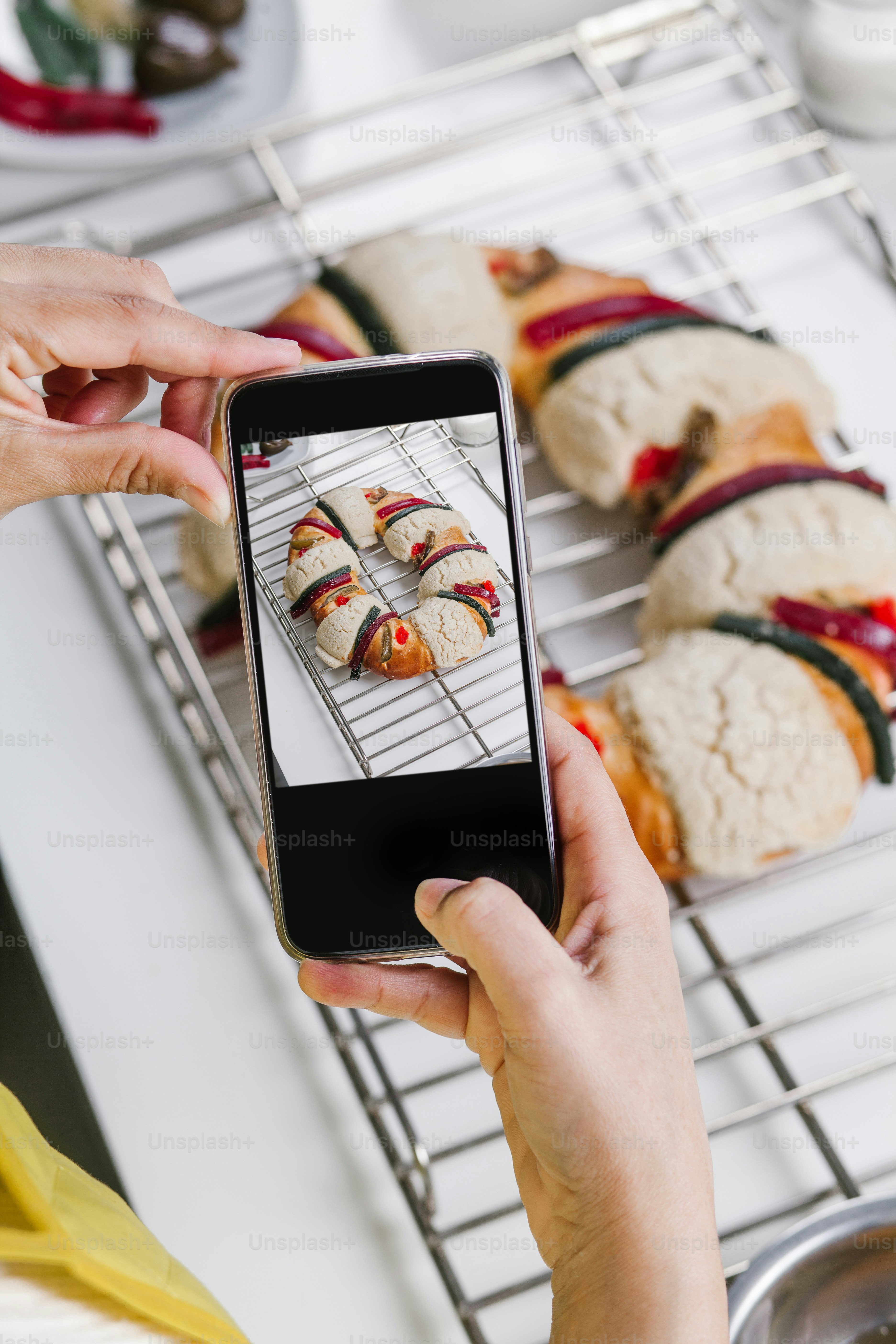 mexican woman habd baking a traditional rosca de reyes or epiphany cake and taking photo with mobile phone in kitchen at home for Kings Day