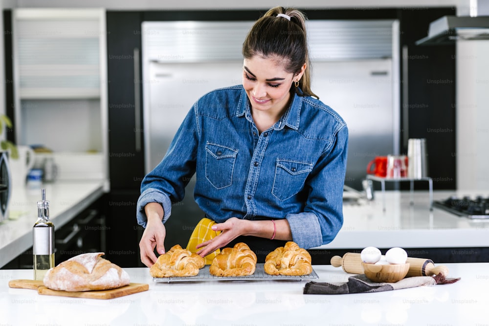 giovane donna latina che cuoce gli ingredienti del croissant in cucina in Messico America Latina