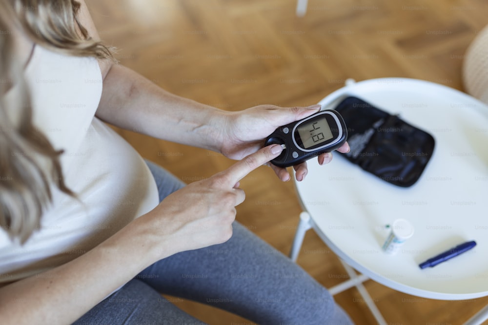 Blood sugar testing at home. Pregnant Woman Checking Blood Sugar Level At Home. Diabetic Checking Blood Sugar Levels. Pregnant Woman checking blood sugar level by glucometer and test stripe at home