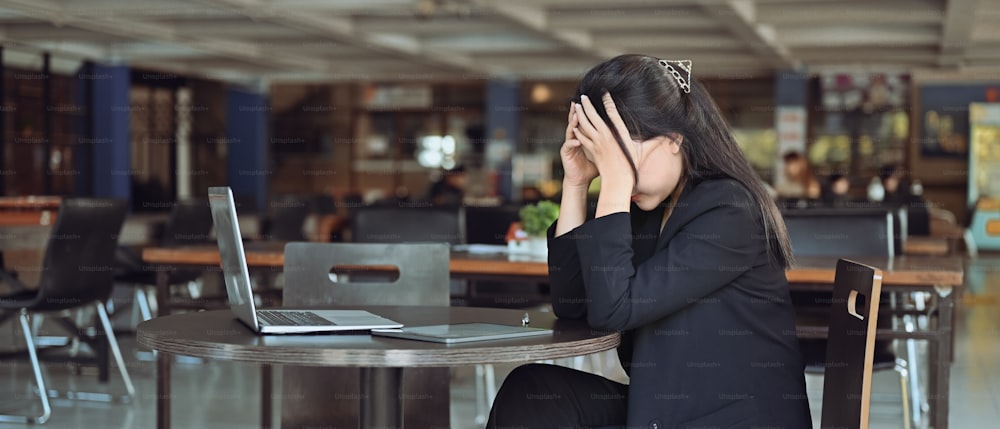 Donna d'affari frustrata che abbatte lo stress mentre è seduta alla scrivania del suo ufficio.