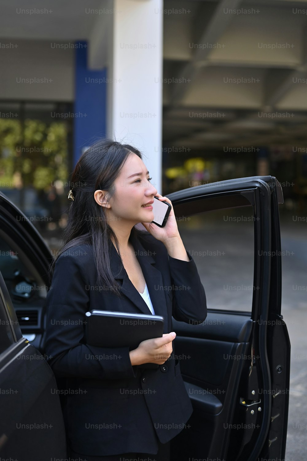 Confident businesswoman standing near her car and talking on mobile phone.