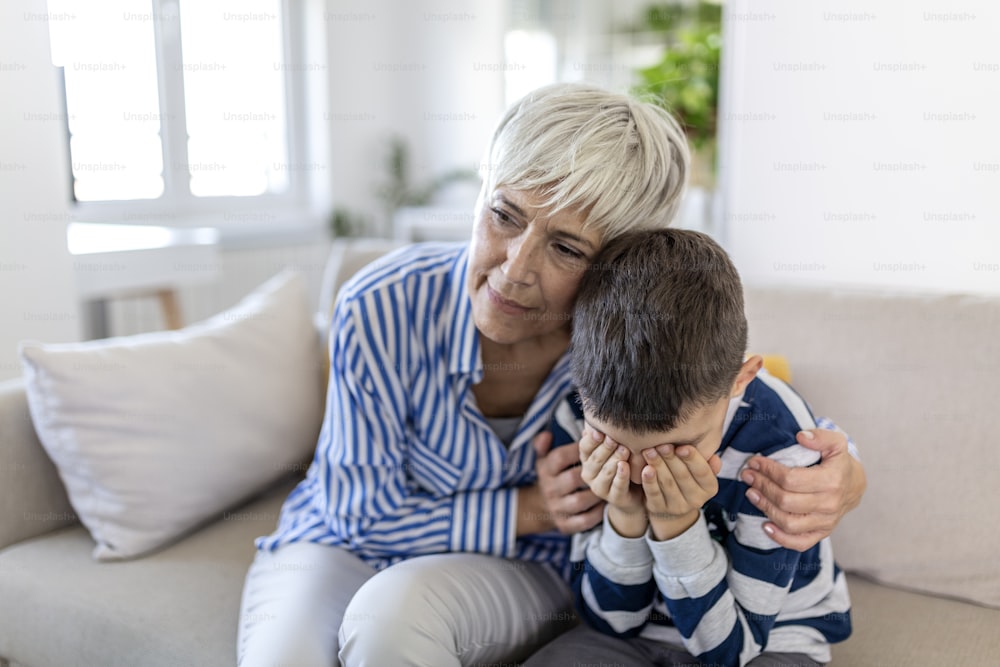 Loving understanding old grandma embracing little crying boy comforting upset grandson, senior caring grandmother hugging child consoling kid in tears, grannys empathy support for grandchild