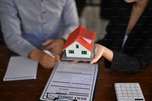 Young couple holding small house model. Insurance or loan real estate concept.