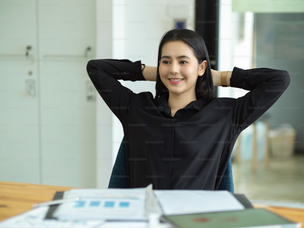 Happy businesswoman with hands behind head, relaxing at comfortable office. satisfied about the company's profit.