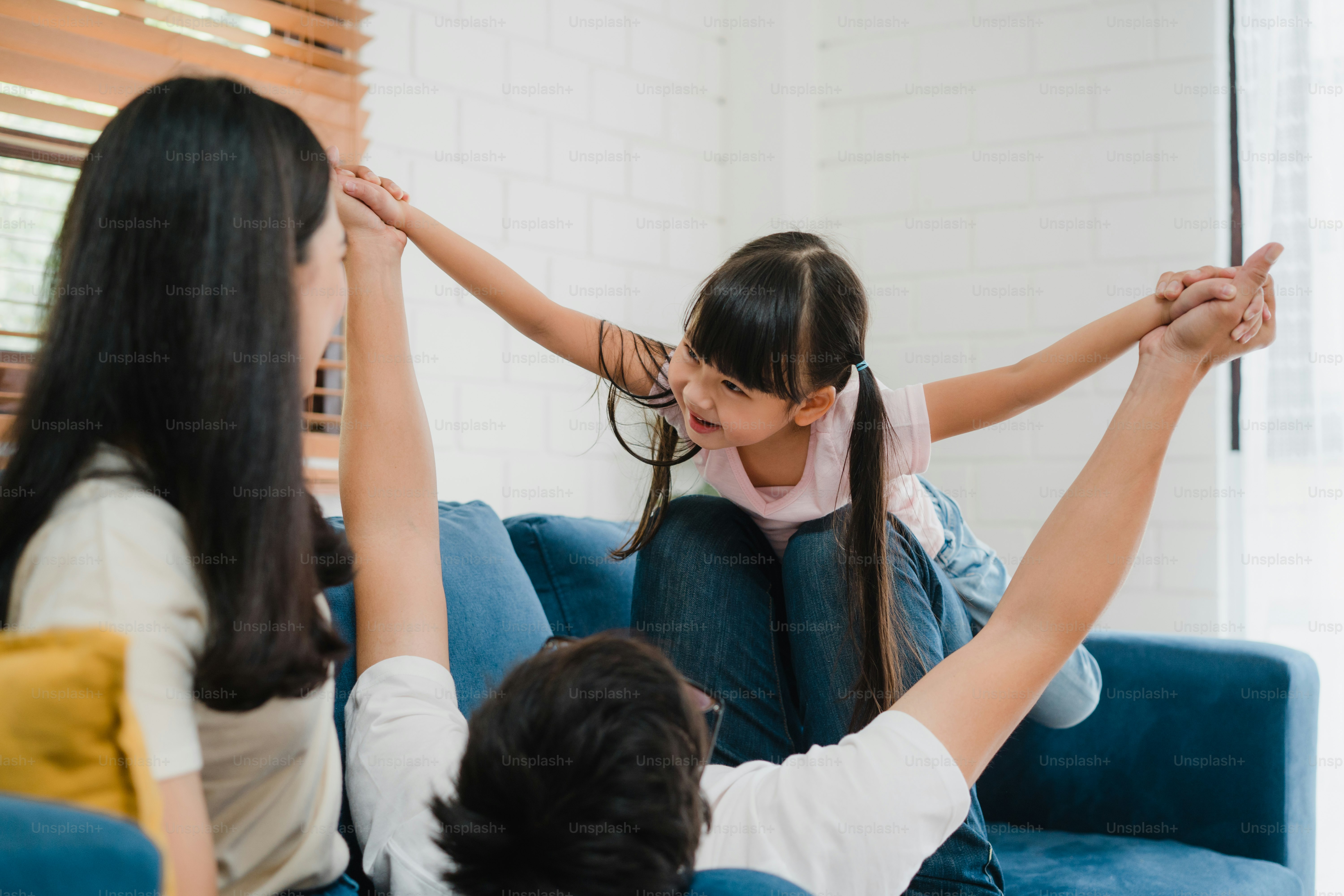 Happy cheerful Asian family dad, mom and daughter having fun playing congratulations with birthday at at house.
