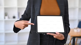 Cropped image of businesswoman holding and showing digital table with white screen.