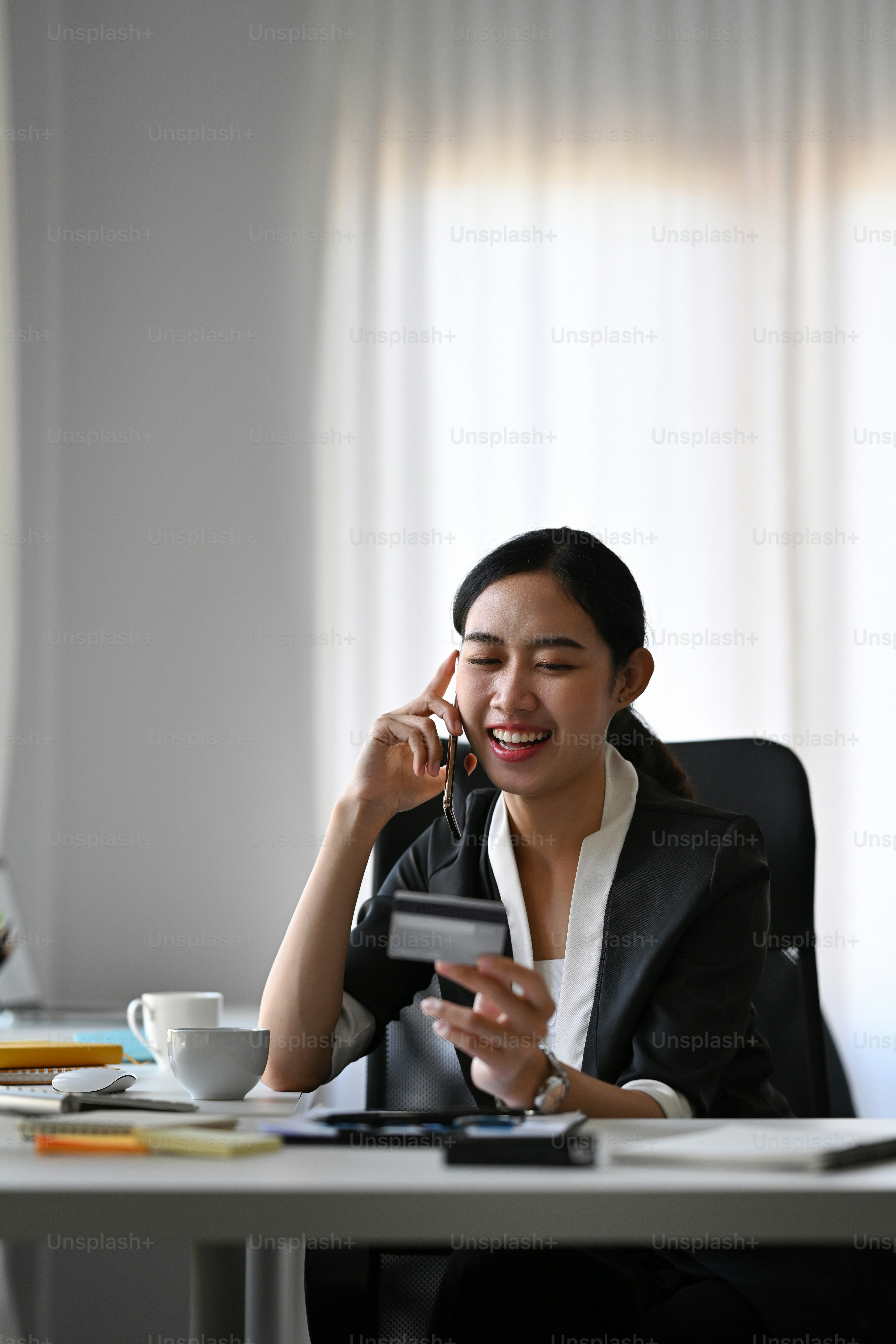 Empresária atraente segurando cartão de crédito e falando no celular com atendimento ao cliente
