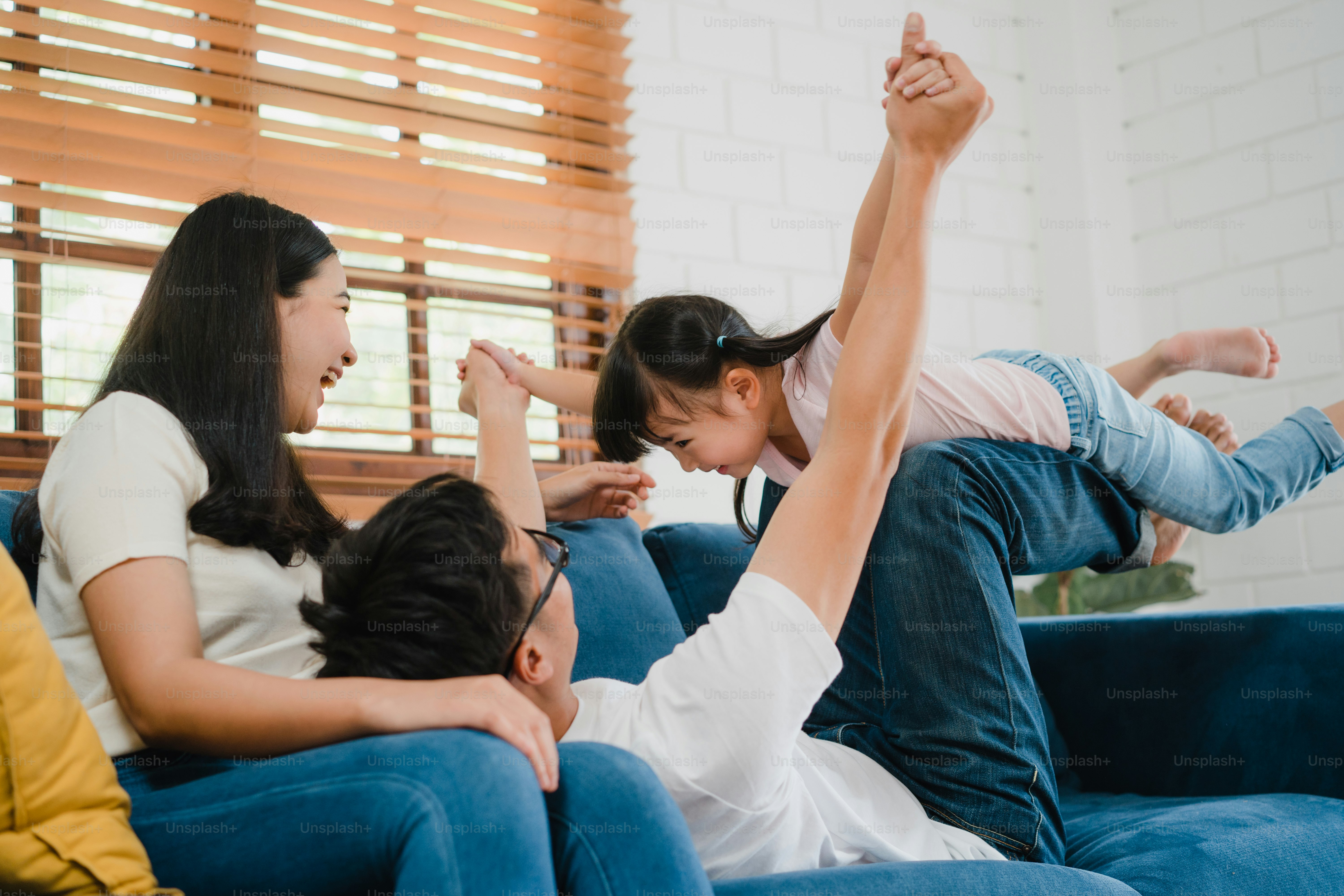 Happy cheerful Asian family dad, mom and daughter having fun playing congratulations with birthday at at house.