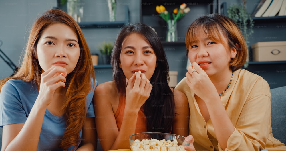 Atractiva asiática encantadora dama grupo de chicas positiva alegre alegre con casual diviértete y disfruta viendo entretenimiento de películas en línea en el sofá de la sala de estar de casa.