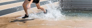 한 고등학생이 트랙 경주 중 첨탑 물 구덩이를 빠져나가면서 물속에서 물놀이를 하고 있��습니다.