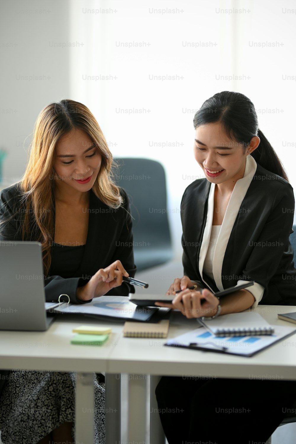 Retrato de dos jóvenes trabajadoras asiáticas discutiendo y planificando planes juntas en el lugar de trabajo moderno.