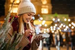 Portrait of happy woman girl eating donuts and enjoying christmas market. Holiday christmas people fun concept