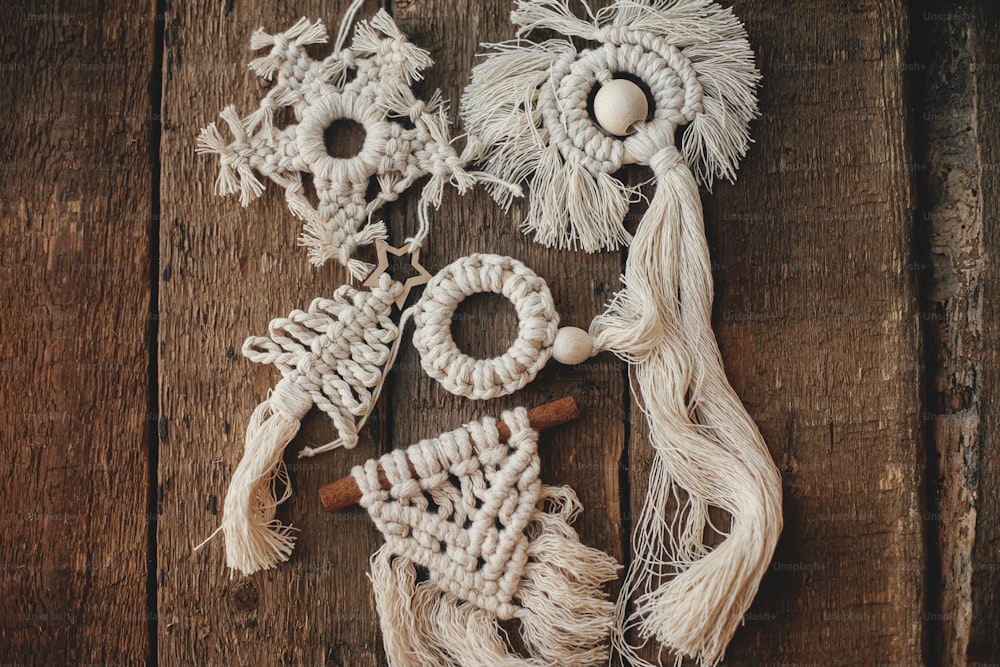 Stilvolle Christbaummakramee Ornamente auf rustikalem Holztisch flach legen. Handgefertigte Boho-Ornamente für den Weihnachtsurlaub. Skandinavisches Dekor, umweltfreundliches Spielzeug.