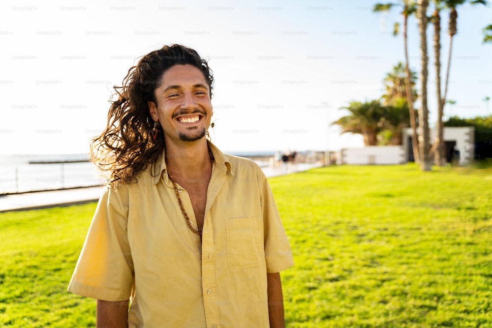 Porträt eines gutaussehenden Hippie-Italieners mit langen Haaren, der schön in die Kamera lächelt. Tourist. Tourismus. Fernweh. Tropen. Reisende.
