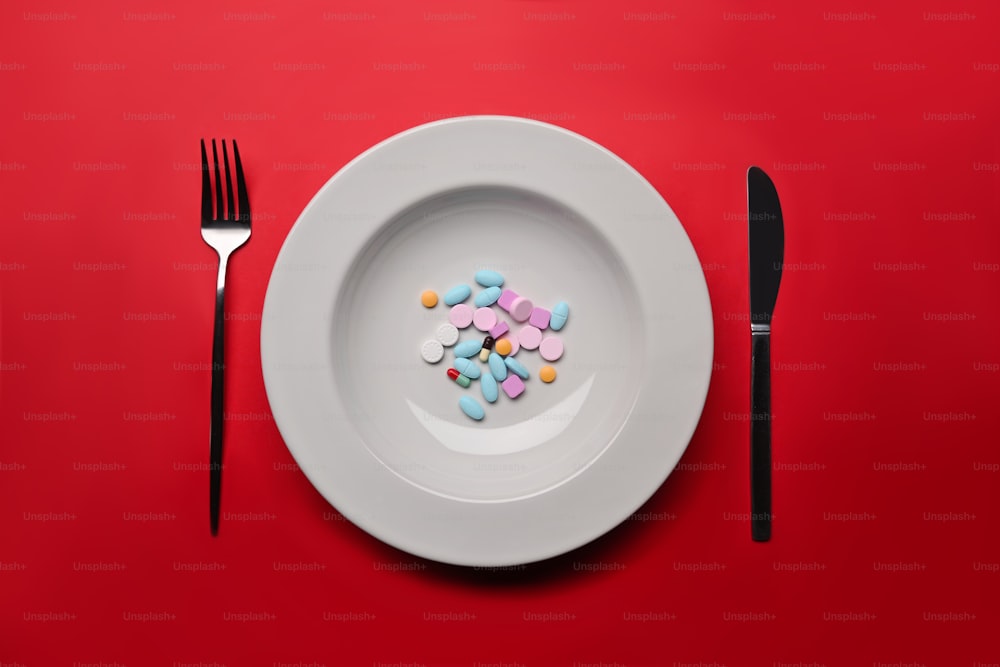 Suplementos como alimento en plato blanco redondo con tenedor y cuchillo. Concepto de vitaminas en lugar de alimentos.