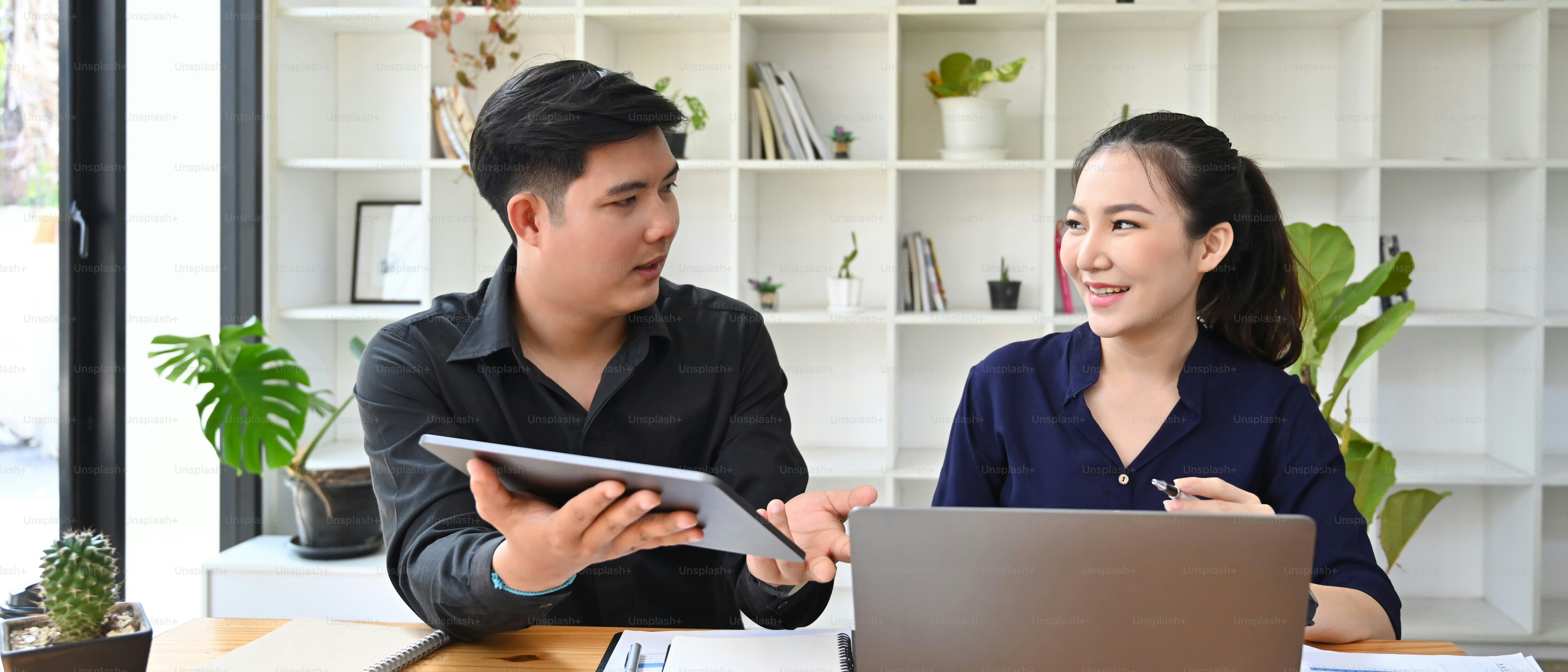 デジタルタブレットを手に、同僚に情報を説明する若いビジネスマン。