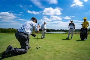 カントリークラブで一緒にゴルフフェアウェイのホールの近くでゴルフをしているアジア人のビジネスマンとシニアCEOのグループ。健康な高齢の男性ゴルファーは、友人と屋外ゴルフスポーツやレジャー活動を楽しんでいます。
