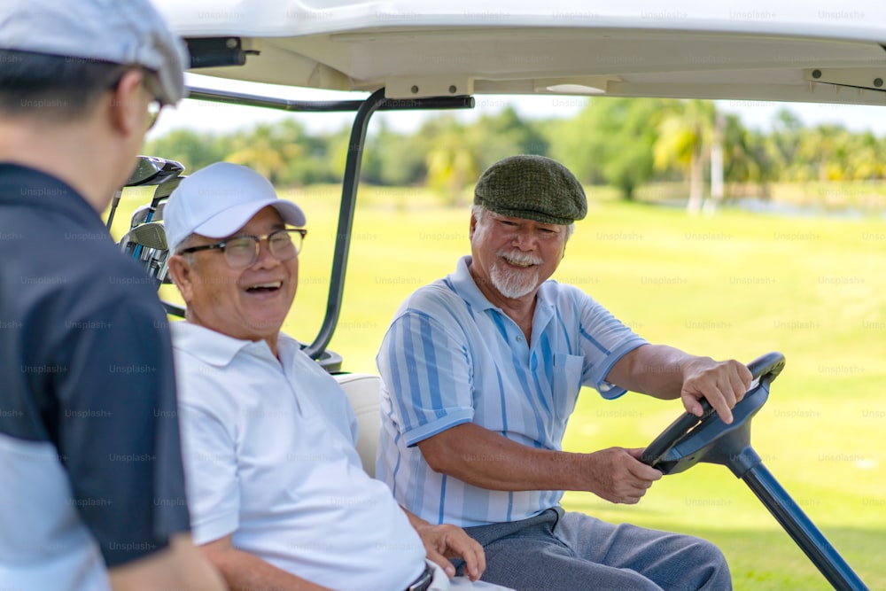 Group of Asian people businessman and senior CEO enjoy outdoor activity lifestyle sport golfing together at country club on summer vacation. Healthy male golfer sitting golf cart with talking together