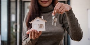 家のモデルと鍵を持つ不動産業者の女性、住宅ローンの提供、住宅保険のコンセプト。