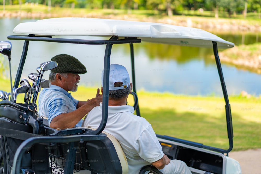 アジアの人々のグループ、ビジネスマン、シニアCEOは、ゴルフカントリークラブで一緒にアウトドアアクティビティ、ライフスタイル、スポーツ、ゴルフを楽しんでいます。夏の晴れた日にゴルフコースでゴルフカートを運転する健康な男性ゴルファー