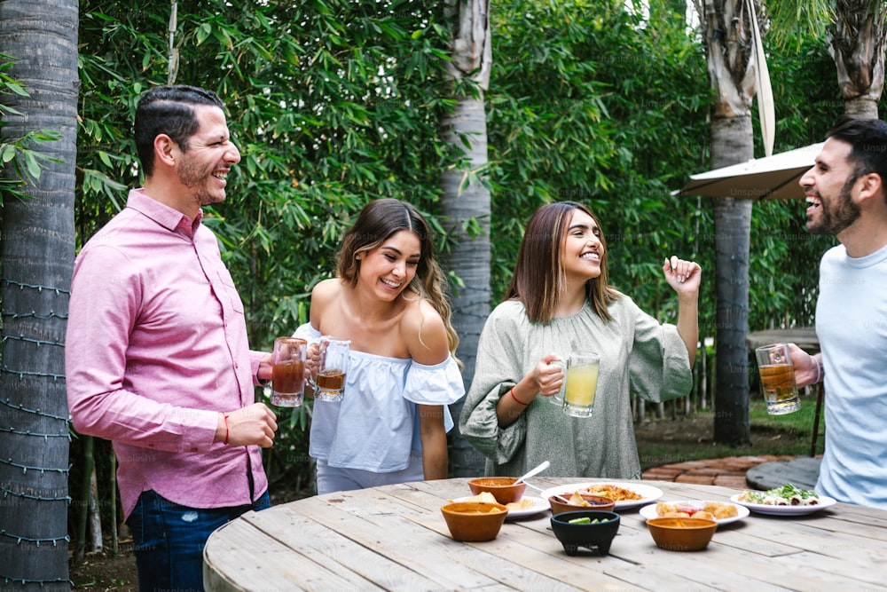 Group of Young latin Friends Meeting For beer, michelada Drinks And mexican Food Making A Toast In Restaurant terrace in Mexico Latin America