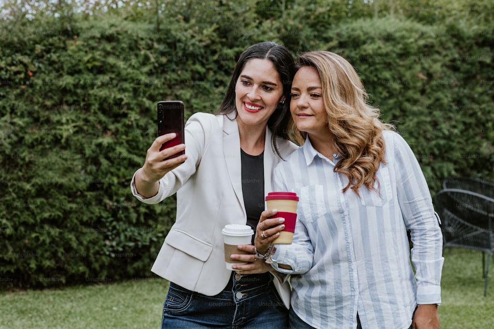 two latin business women taking a photo selfie with mobile phone at terrace office in Mexico Latin America