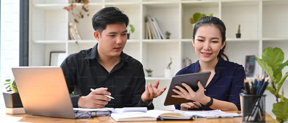 Two young business people discussing new project together in office.