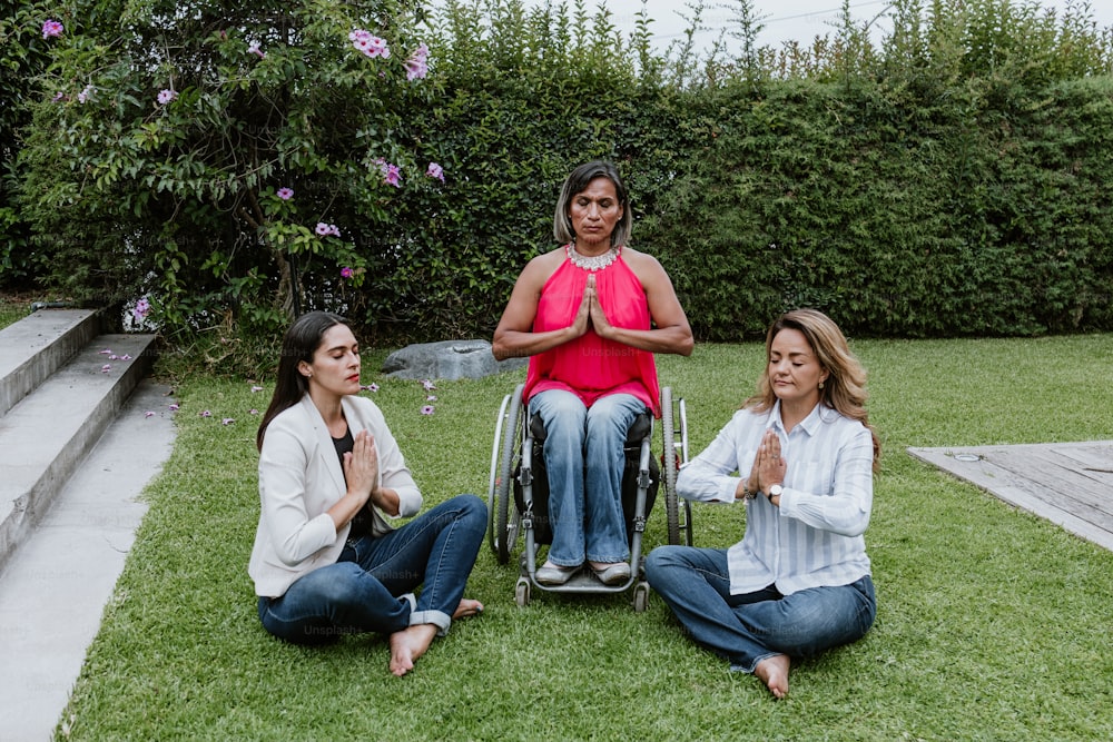 latin business woman transgender on wheels chair and friends sitting on grass and meditating at terrace office in Mexico Latin America
