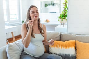 Mulher grávida fazendo um teste caseiro de auto-swabbing para COVID-19 em casa com o kit Antigen. Introduzindo bastão nasal para verificar a infecção do Coronavírus. Quarentena, pandemia.