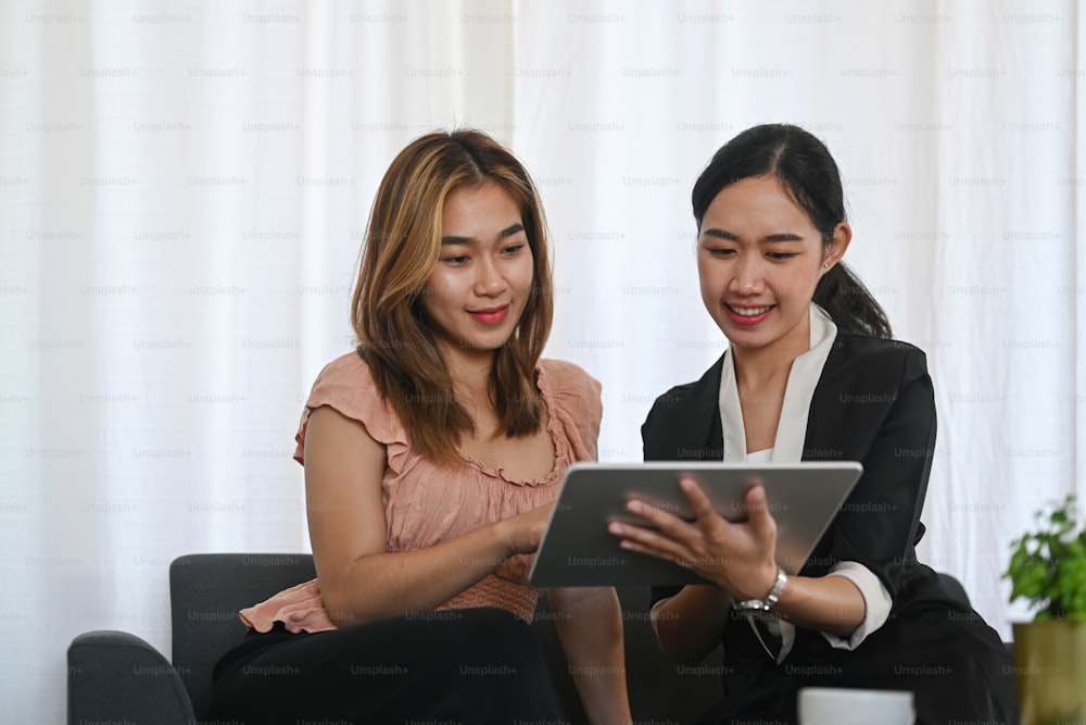 Friendly asian female agent offering health insurance for young woman in office.