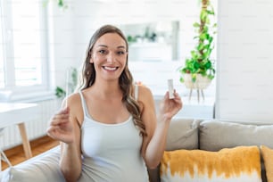Nahaufnahme der Hand einer schwangeren Frau, die ein negatives Testgerät hält. Glückliche Schwangere zeigt ihr negatives Coronavirus - Covid-19-Schnelltest. Coronavirus