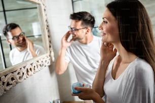 Young couple going through morning routine in the bathroom applying face cream.