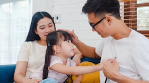 Feliz alegre família asiática pai, mãe e filha jogando jogo engraçado como médico se divertindo no sofá em casa.