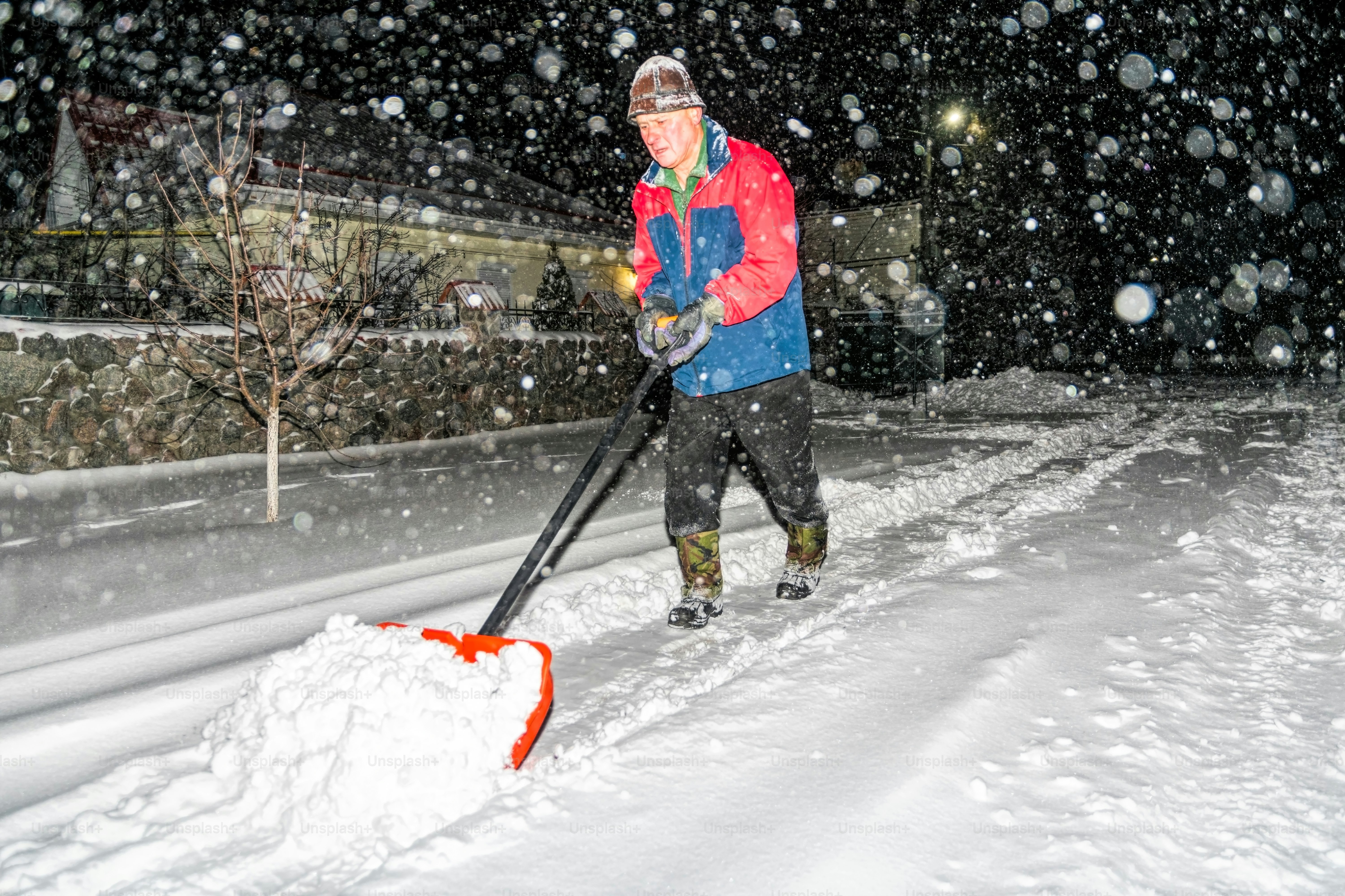 elderly man with a shovel in his hands clears the street after a heavy snowfall. Man at seasonal work