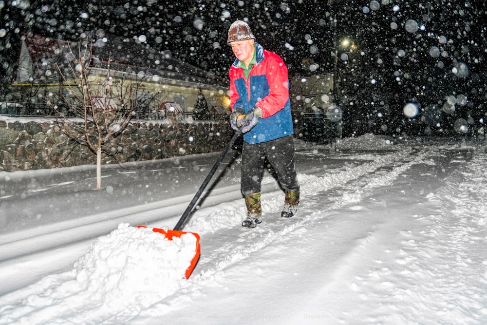 elderly man with a shovel in his hands clears the street after a heavy snowfall. Man at seasonal work