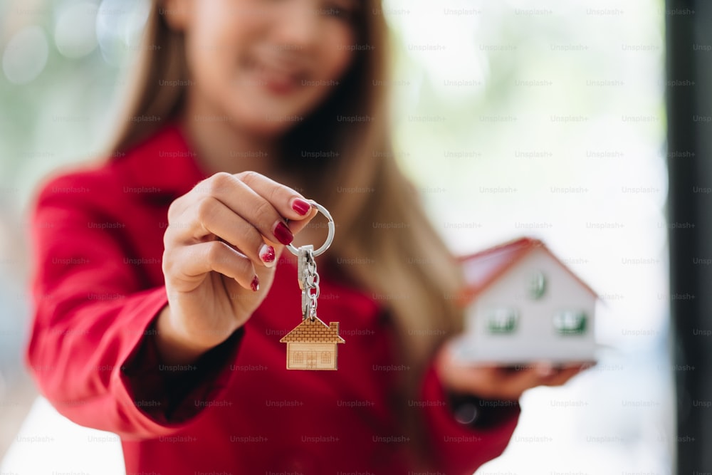 Agente de bienes raíces que tiene la llave de la casa a su cliente después de firmar el contrato en la oficina, concepto de bienes raíces, mudanza o alquiler de propiedad.