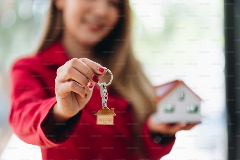 real estate agent holding house key to his client after signing contract agreement in office, concept for real estate, moving home or renting property.