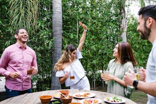 Group of Young latin Friends Meeting For beer, michelada Drinks And mexican Food Making A Toast In Restaurant terrace in Mexico Latin America