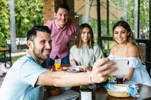 Group of latin friends taking a photo selfie and eating mexican food in the restaurant terrace in Mexico Latin America