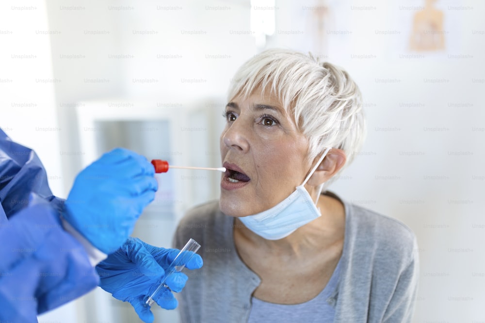 Physician wearing personal protective equipment performing a Coronavirus COVID-19 PCR test, patient nasal NP and oral OP swab sample specimen collection process, viral rt-PCR DNA diagnostic procedure
