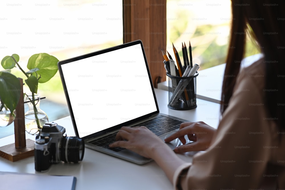 Freelancer do sexo feminino trabalhando com laptop em seu escritório em casa.