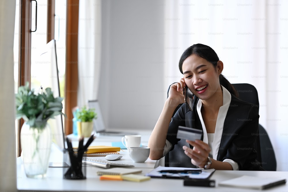 Beautiful asian woman calling with customer service for concerning information on credit card.