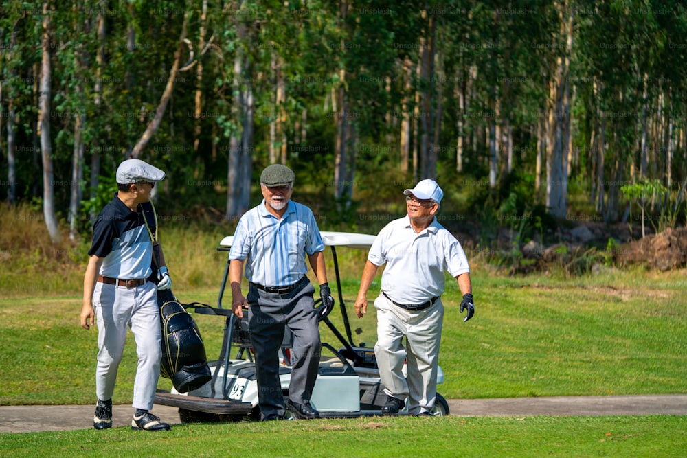 Group of Asian people businessman and senior CEO golfing near the hole on golf fairway together at country club. Healthy elderly man golfer enjoy outdoor golf sport and leisure activity with friends.