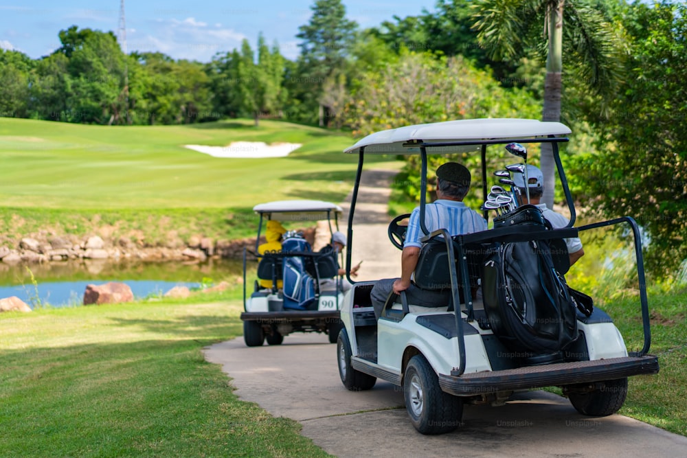 Group of Asian people businessman and senior CEO enjoy outdoor activity lifestyle sport golfing together at golf country club. Healthy men golfer driving golf cart on golf course in summer sunny day